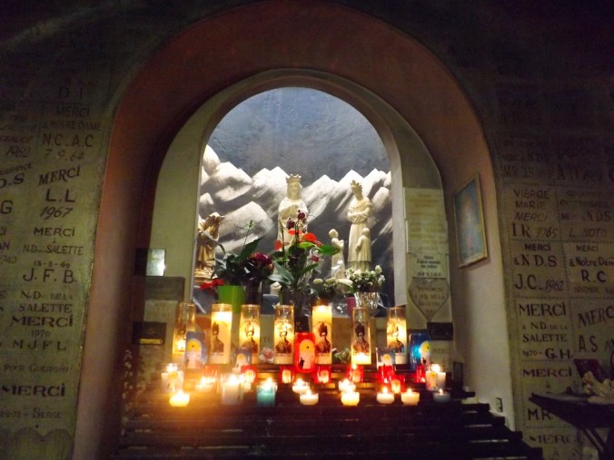 bougies et ex voto devant la stautue de notre dame de la salette