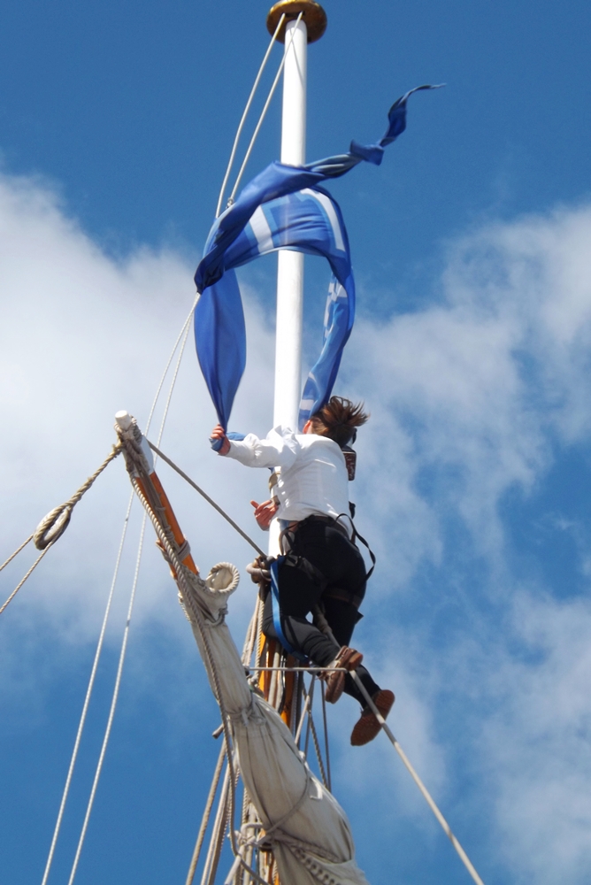 matelot qui attache le drapeau au sommet du mat du Shtandart russe